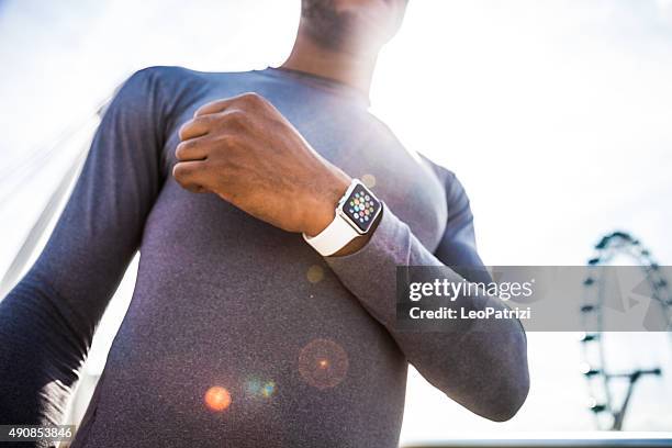 man checking the time for a run in the city - apple watch stock pictures, royalty-free photos & images