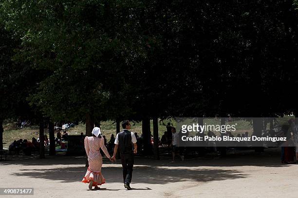 Couple dressed as 'chulapos' walk at Pradera de San Isidro park during the San Isidro festivities on May 15, 2014 in Madrid, Spain. During the...