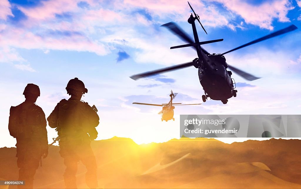 Helicóptero Militar e Exército dos Soldados no pôr-do-sol