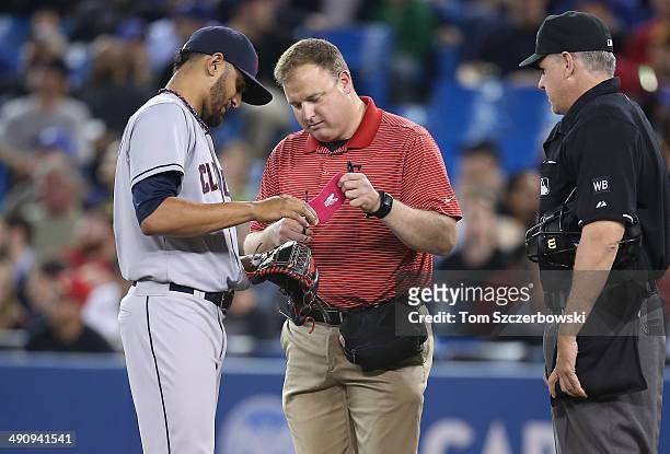 Danny Salazar of the Cleveland Indians is told to remove a piece of equipment from his glove hand by home plate umpire Paul Emmel as the traner comes...