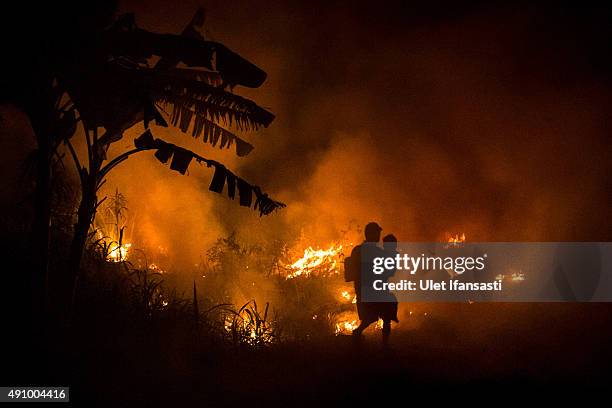 Man carries his son as he walks through the haze on the way to his house as a fire burned peatland and fields at Ogan Ilir district on October 2,...