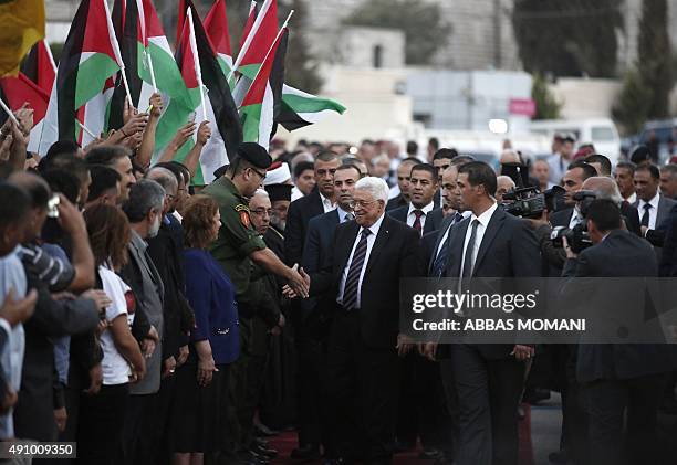 Palestinians wave their national flags as they greet their president Mahmud Abbas upon his arrival from New York on October 2, 2015 where he attended...