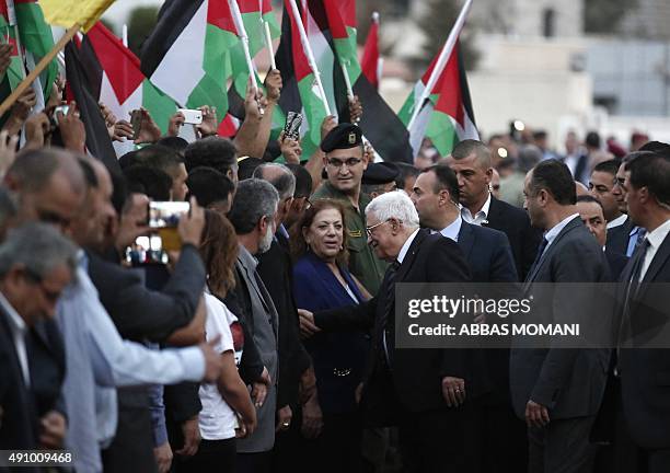 Palestinians wave their national flags as they greet their president Mahmud Abbas upon his arrival from New York on October 2, 2015 where he attended...