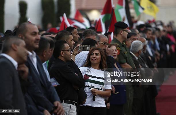 Palestinian woman uses her phone to take photos as she waits with a crowd to greet president Mahmud Abbas upon his arrival from New York on October...