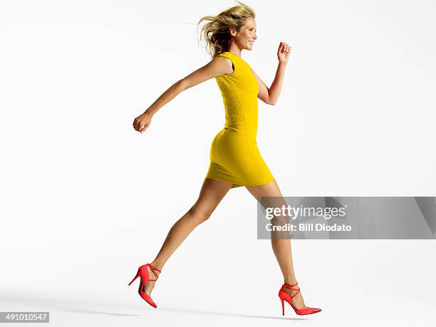 woman in colorful dress jumping in studio - minijurk stockfoto's en -beelden