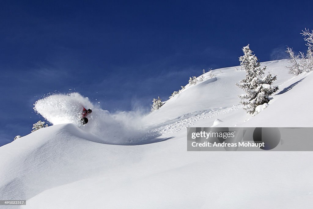A snowboarder does a powder turn