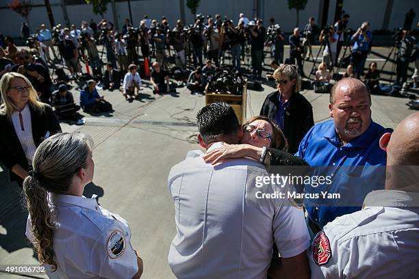 Governor Kate Brown hugs first responders gathered behind her after a press conference outside the Roseburg Fire Department Administration building...