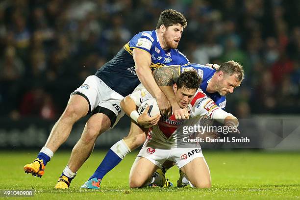 Louie McCarthy-Scarsbrook of St. Helens R.F.C falls from a tackle by Jamie Peacock and Mitch Garbutt of Leeds Rhinos during the First Utility Super...