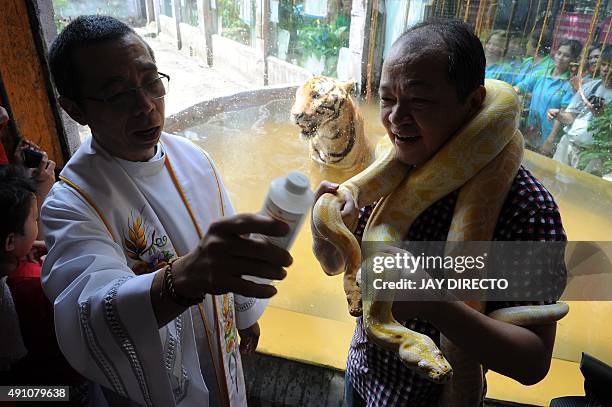 Roman Catholic priest blesses an albino Burmese python and other animals with holy water on the eve of World Animal Day at Malabon Zoo in suburban...