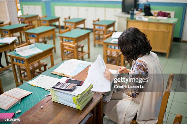 teacher marks exam papers in classroom - teacher desk foto e immagini stock