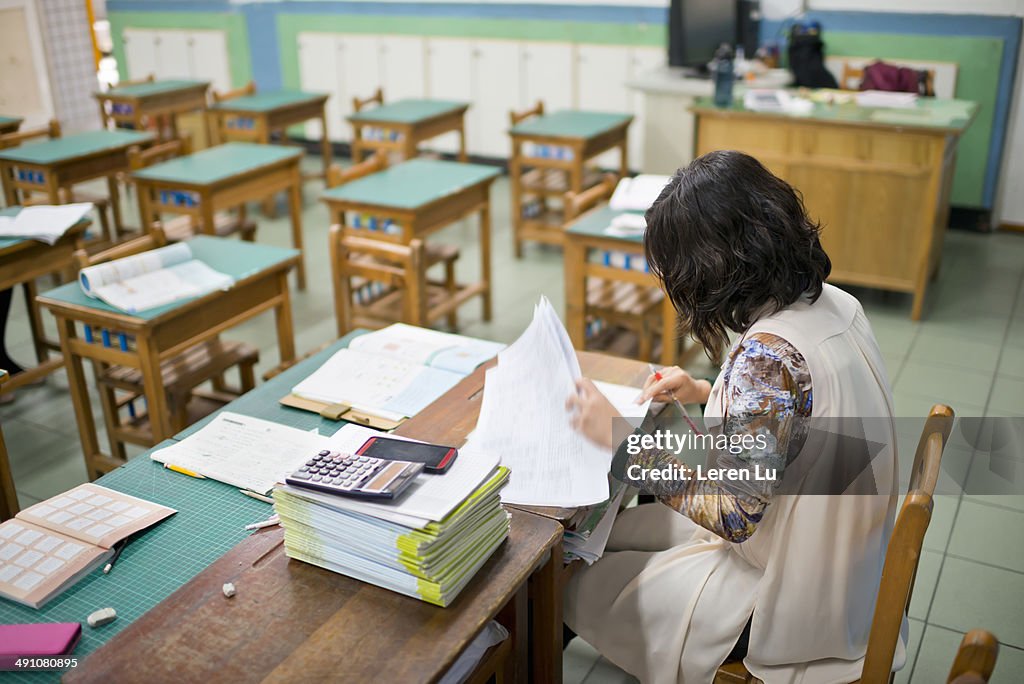 Teacher marks exam papers in classroom