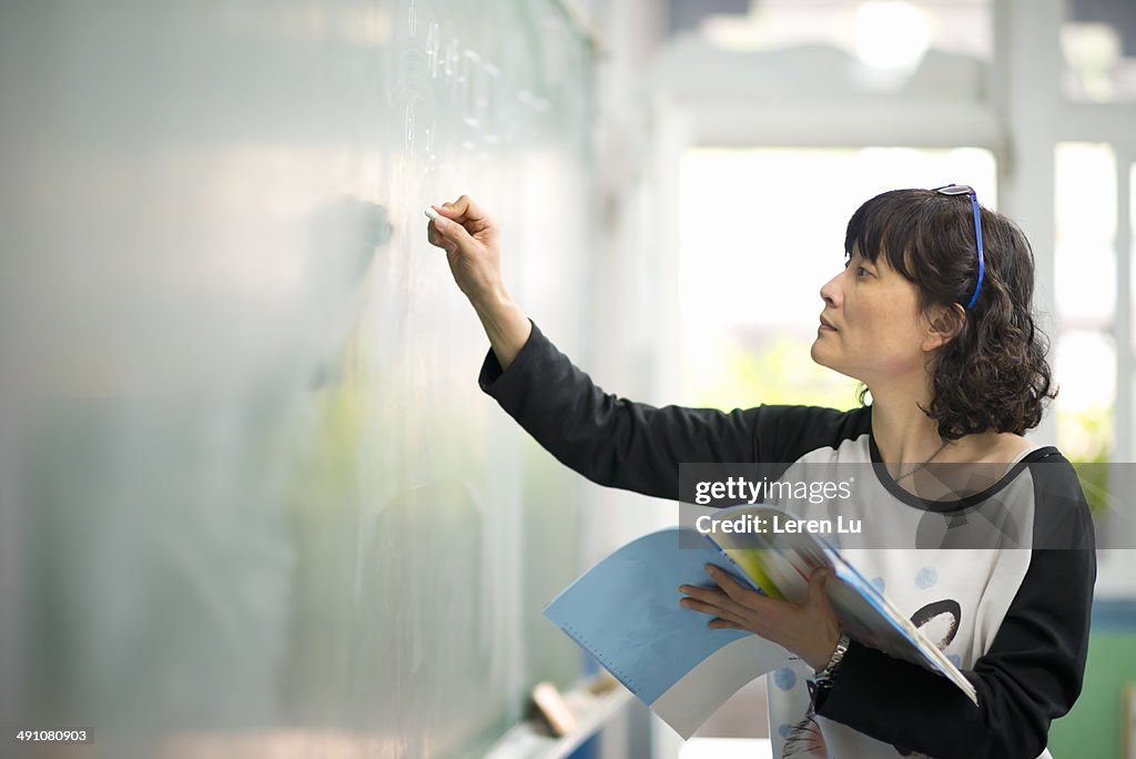 Teacher writing on chalkboard