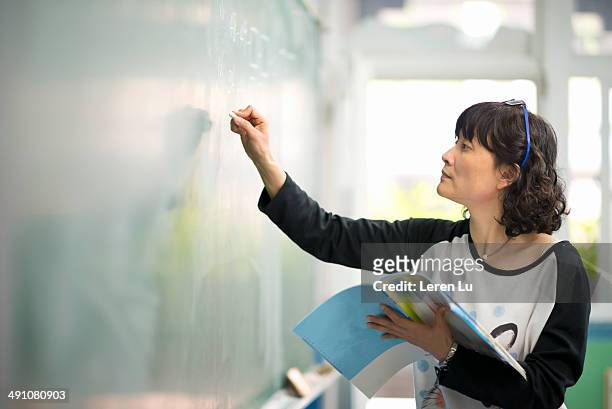 teacher writing on chalkboard - blackboard women stock pictures, royalty-free photos & images