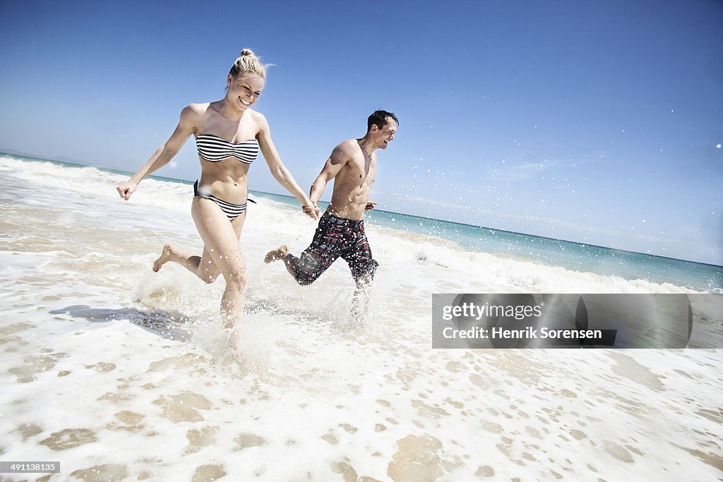 Couple running through waves