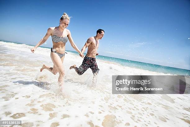 couple running through waves - insel fuerteventura stock-fotos und bilder