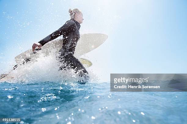 female surfer on the beach - beach hold surfboard stock-fotos und bilder