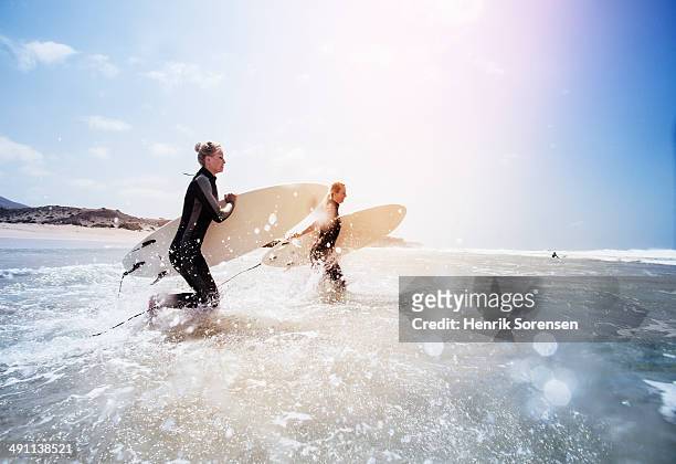 two female surfers on the beach - surf imagens e fotografias de stock