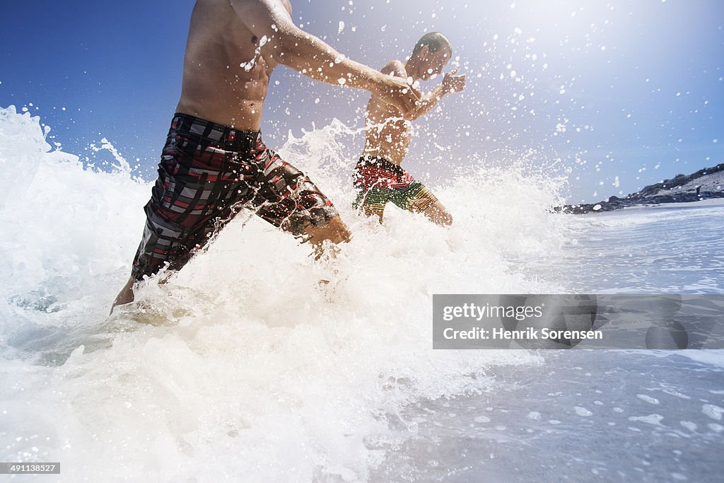 Two men running through waves