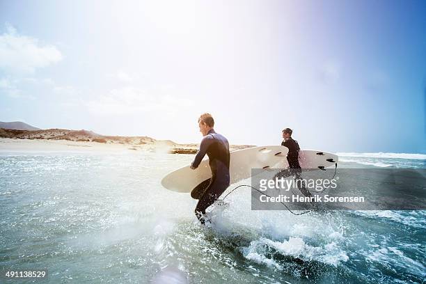 male surfers on the beach - fuerteventura fotografías e imágenes de stock
