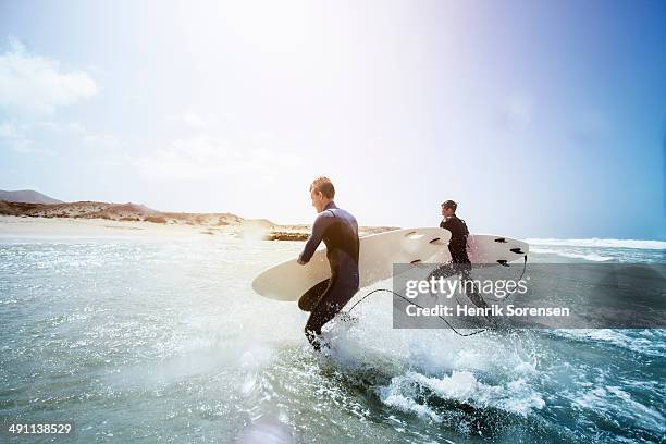 male surfers on the beach - waves crashing foto e immagini stock