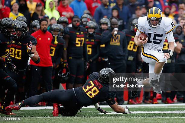 Quarterback Jake Rudock of the Michigan Wolverines eludes the tackle of Brett Zanotto of the Maryland Terrapins during the first half at Byrd Stadium...