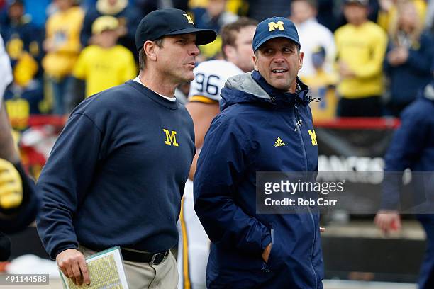 Head coach Jim Harbaugh of the Michigan Wolverines jogs off the fiedl with his brother Baltimore Ravens head coach John Harbaugh following halftime...