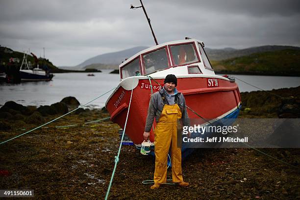 Donald John Macleod paints a fishing boat in Scalpay on May 15, 2014 in Harris, Scotland. The Isles of Lewis and Harris lie in the Outer Hebrides and...