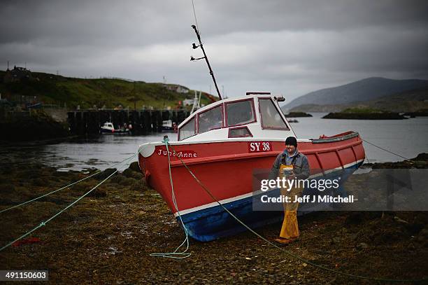 Donald John Macleod paints a fishing boat in Scalpay on May 15, 2014 in Harris, Scotland. The Isles of Lewis and Harris lie in the Outer Hebrides and...