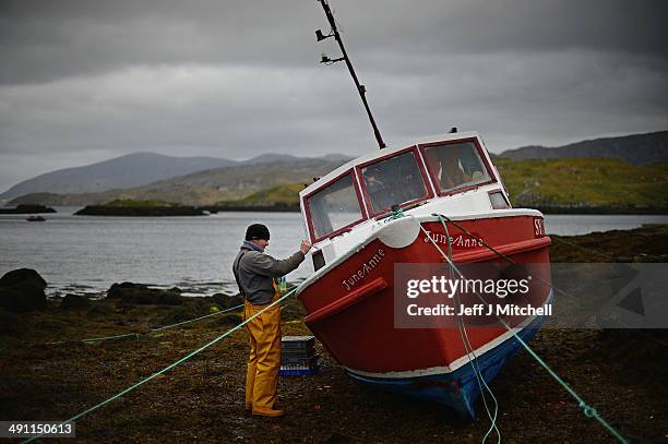 Donald John Macleod paints a fishing boat in Scalpay on May 15, 2014 in Harris, Scotland. The Isles of Lewis and Harris lie in the Outer Hebrides and...