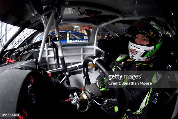 Kyle Busch, driver of the Interstate Batteries Toyota, sits in his car in the garage area during practice for the NASCAR Sprint Cup Series AAA 400 at...