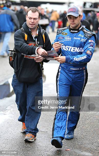 Ricky Stenhouse Jr., driver of the Fastenal Ford, right, signs his autograph for a fan in the garage area during practice for the NASCAR Sprint Cup...