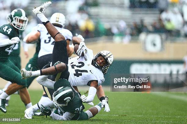 Frankie Williams of the Purdue Boilermakers runs the ball and is tackled by Jalen Watts-Jackson of the Michigan State Spartans at Spartan Stadium on...