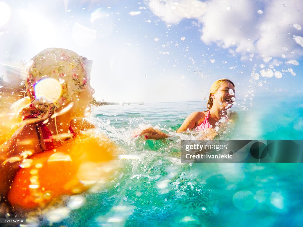 Mother and daughter splashing water in sea