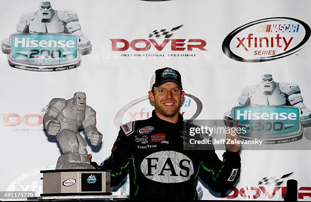 Regan Smith, driver of the Fire Alarm Services Chevrolet, poses with the Miles the Monster Trophy in Victory Lane after winning the NASCAR XFINITY...