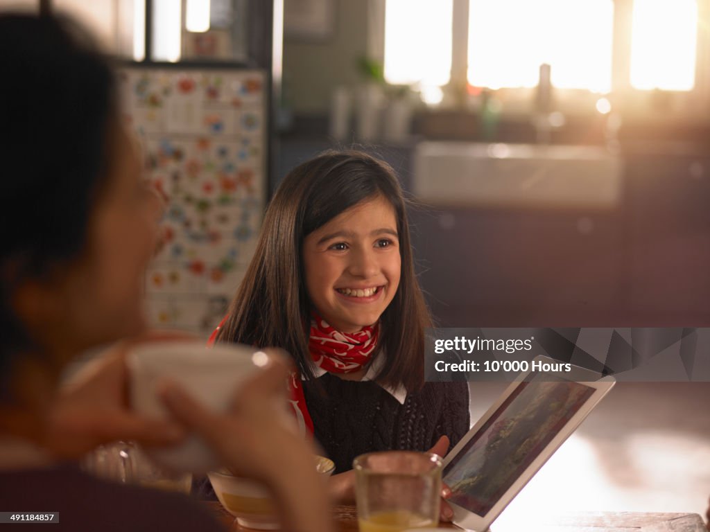 Girl at the breakfast table with a tablet computer