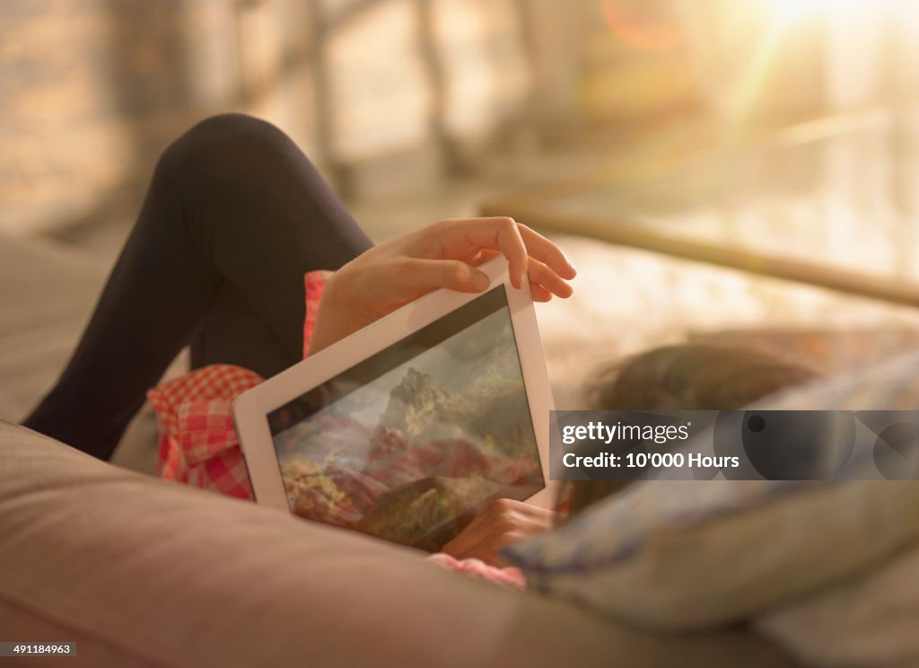 A girl relaxing at home watching a film on an tablet computer