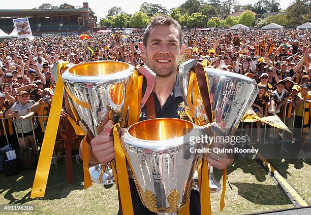 Luke Hodge the captian of the Hawks poses with the 2013, 2014 and 2015 premiership trophies during the Hawthorn Hawks AFL Grand Final fan day at...