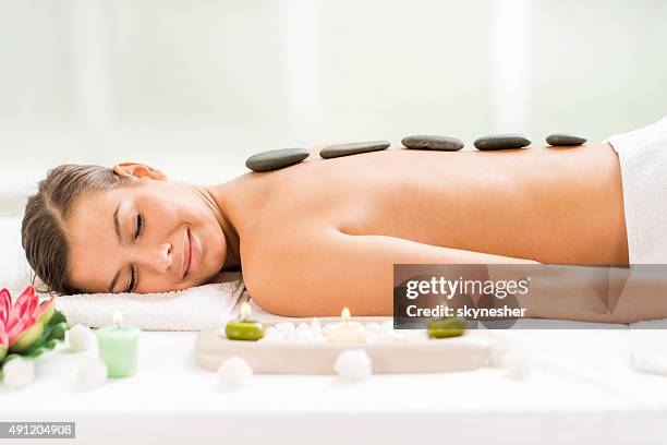 mujer joven recibiendo tratamiento con terapia de piedras. - terapia lastone fotografías e imágenes de stock