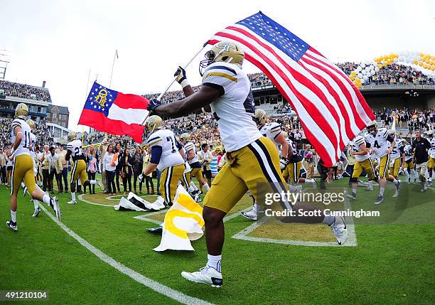 KeShun Freeman of the Georgia Tech Yellow Jackets carries the American flag as he takes the field against the North Carolina Tar Heels on October 3,...