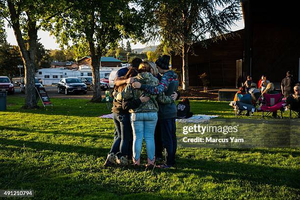 Friends of the late Rebecka Ann Carnes, an Umpqua Community College mass shootings victim, embrace one another in prayer before the start of a...