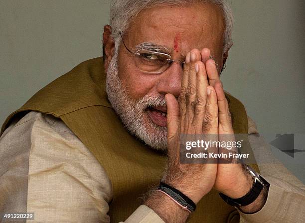 Leader Narendra Modi gestures to supporters as he sits with his mother Heeraben Modi, not seen, on her front porch after seeking her blessing on May...