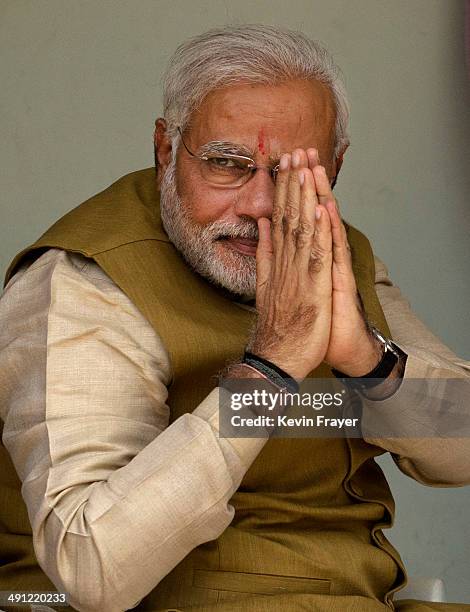 Leader Narendra Modi gestures to supporters as he sits with his mother Heeraben Modi, not seen, on her front porch after seeking her blessing on May...