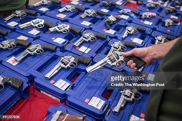 People look at handguns as thousands of customers and hundreds of dealers sell, show, and buy guns and other items during The Nation's Gun Show at...
