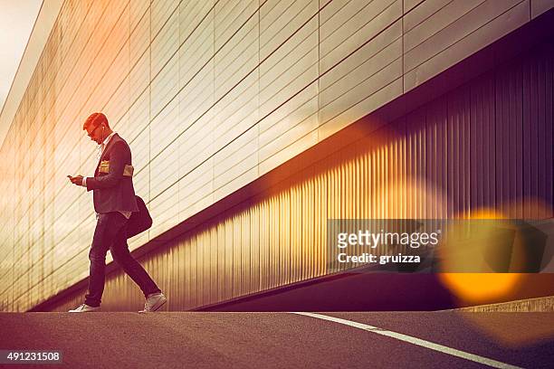 young casual businessman using smartphone in the urban environment - high contrast bildbanksfoton och bilder
