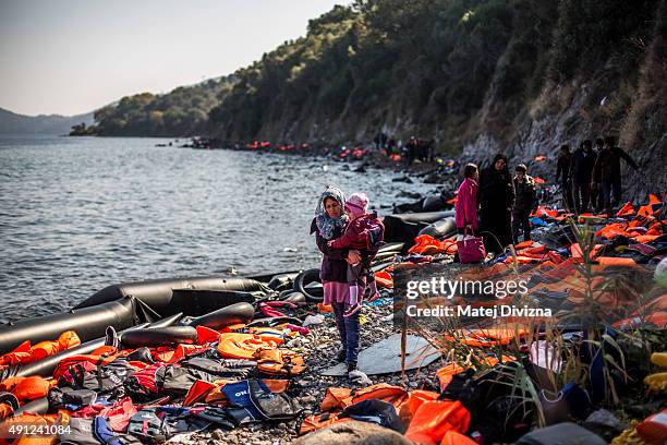 Woman carries her child as she arrives with other refugees on the shores of the Greek island of Lesbos after crossing the Aegean sea from Turkey on...