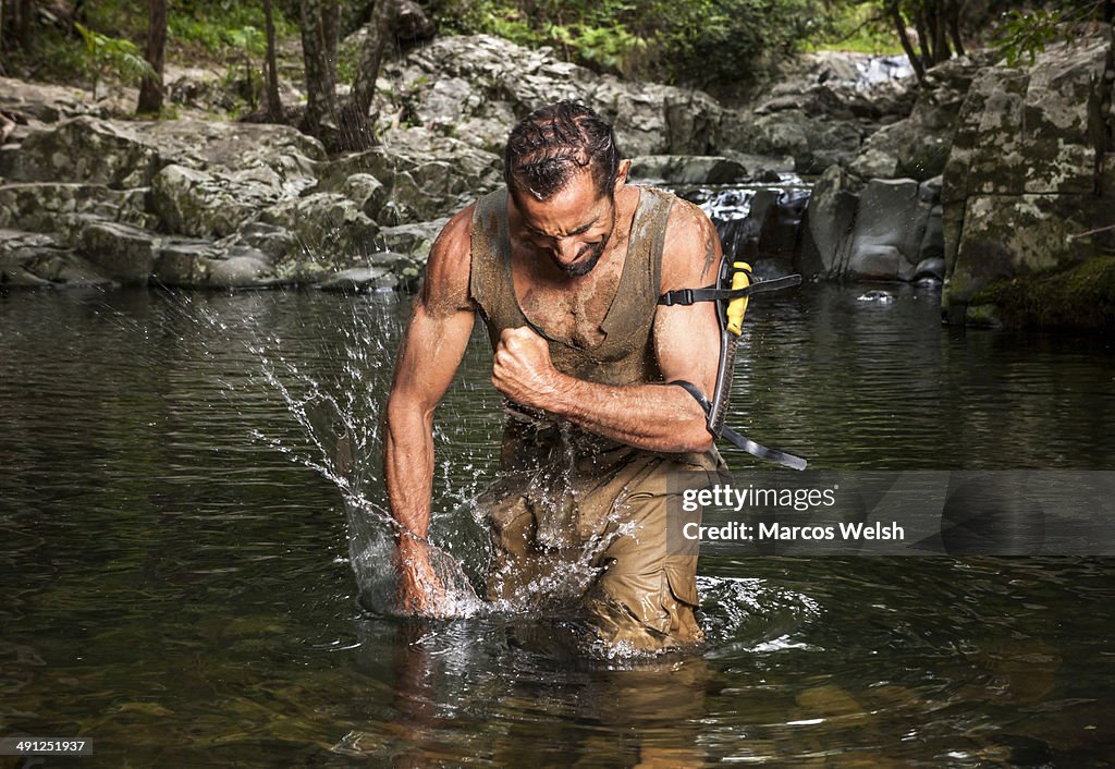 Man lost in nature, frustrated punching water