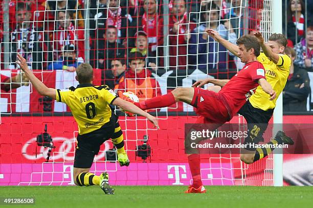 Thomas Mueller of Muenchen scores the opening goal against Sven Bender of Dortmund and his team mate Lukasz Piszczek during the Bundesliga match...