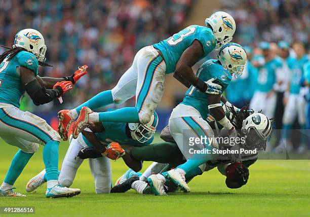 Chris Ivory of the New York Jets is tackled by Jelani Jenkins of the Miami Dolphins and Michael Thomas of the Miami Dolphins during the game at...