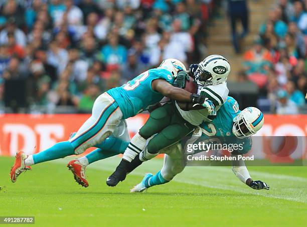 Darrin Walls of the New York Jets is tackled by Jelani Jenkins of the Miami Dolphins and Reshad Jones of the Miami Dolphins during the game at...