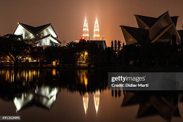 The skyline of Kuala Lumpur, including the famous Petronas Towers, reflecting in a lake north of the city in Titawangsa. Kuala Lumpur is Malaysia...